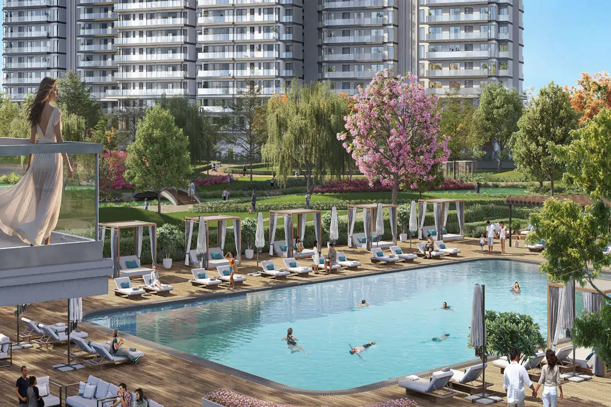 Emaar Serenity Hills Sector 86 Gurgaon resort-style swimming pool with luxury cabanas, wooden deck loungers, and lush green landscape overlooking residential towers in New Gurugram